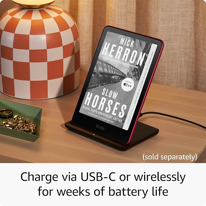 Kindle Paperwhite charging on wireless dock with weeks of battery life.