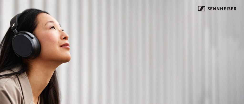Woman wearing high-end Sennheiser headphones outdoors, highlighting premium sound quality and design